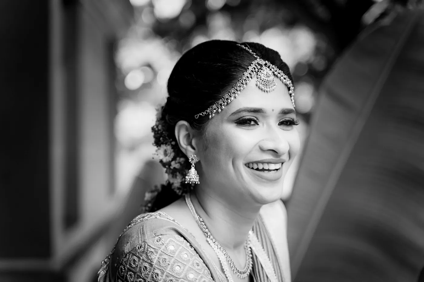 Black and white of Medha laughing with her head tilted, her gold headpiece catching the light