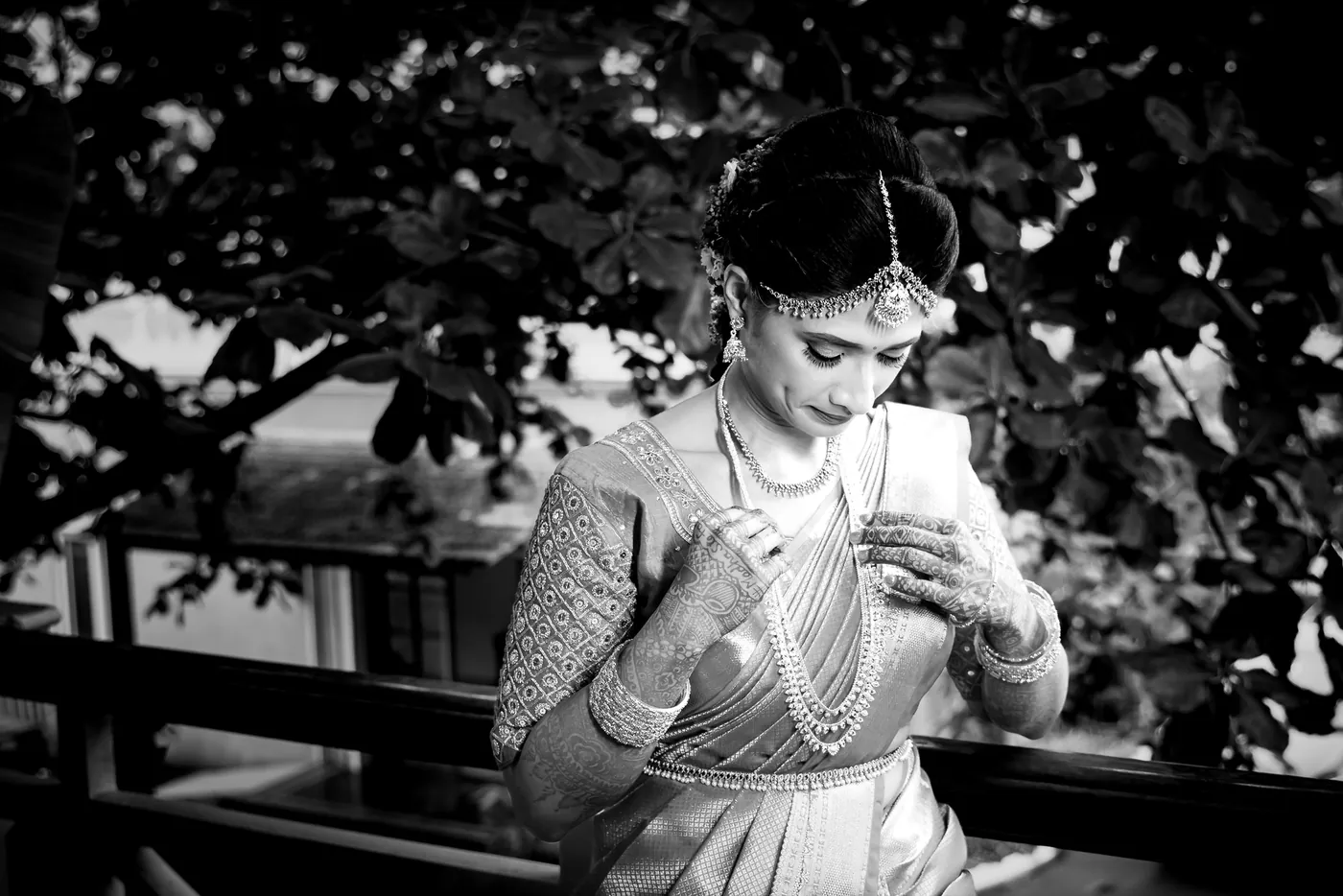 Black and white of Medha smiling down at something small held between her fingers
