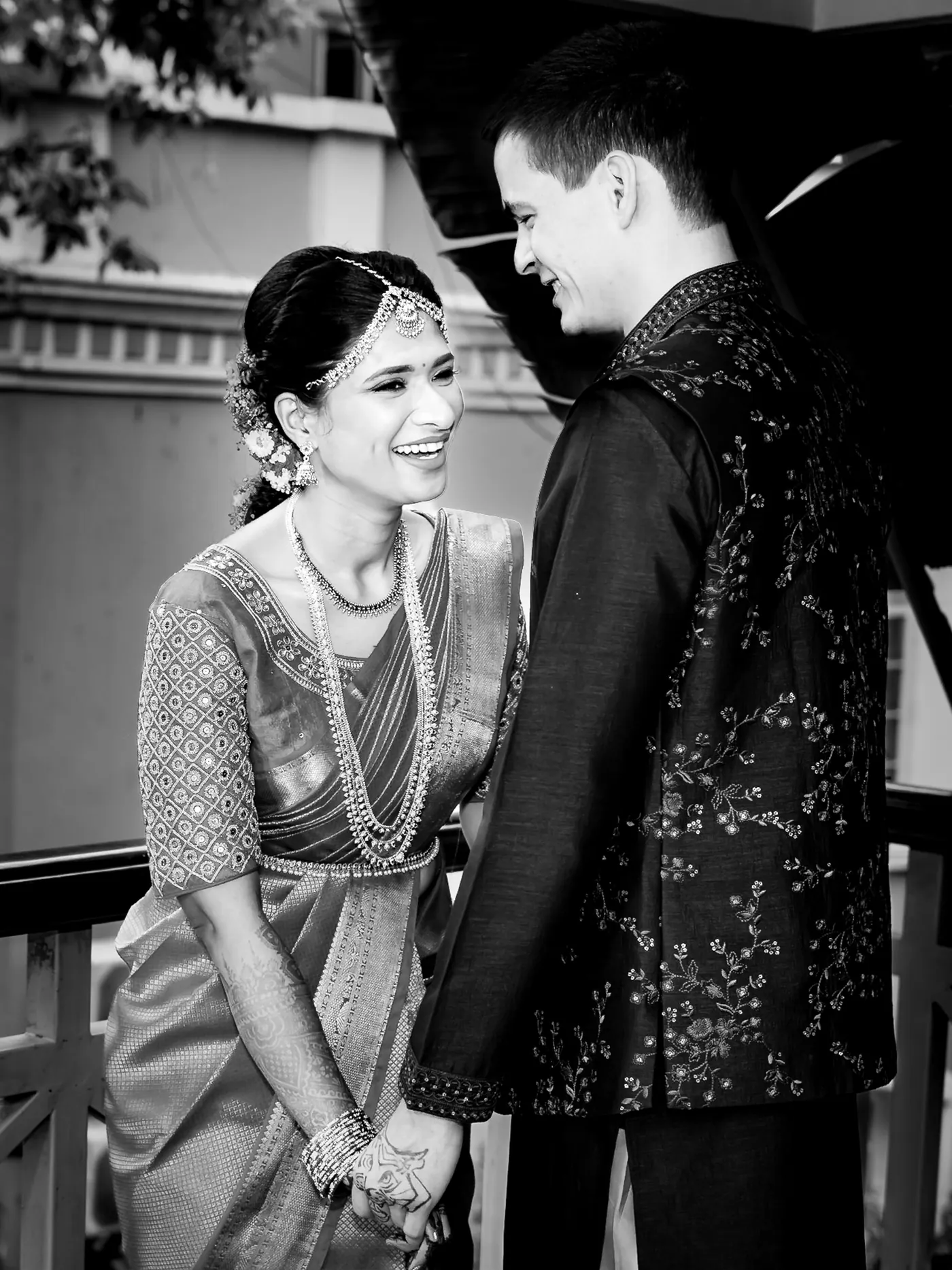 Black and white of Medha laughing as Stefan looks down at her and holds her hand