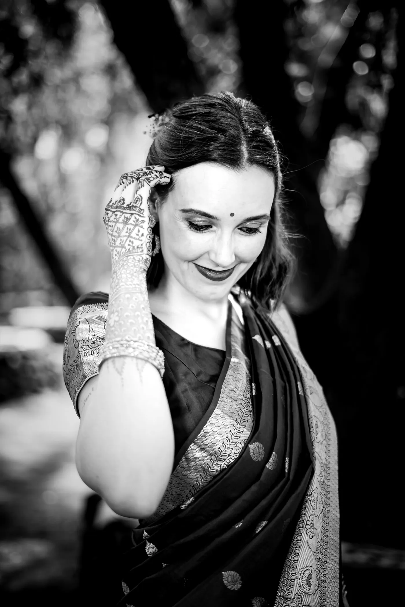 Black and white of Stefan's sister tucking her hair behind her ear, henna on her hand, eyes cast down