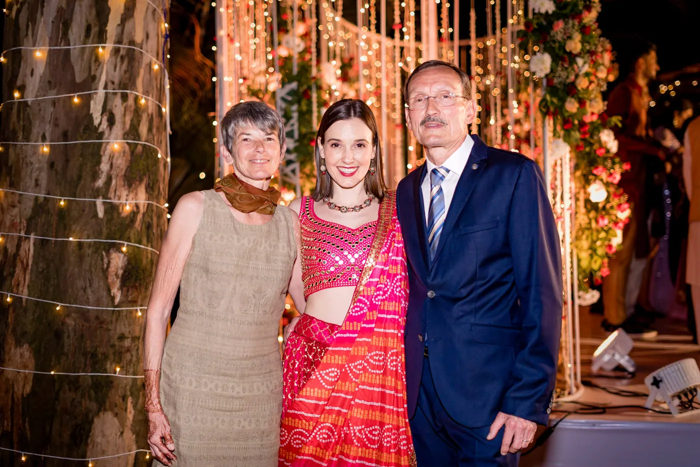 Three family members smile together in front of the hanging lights backdrop