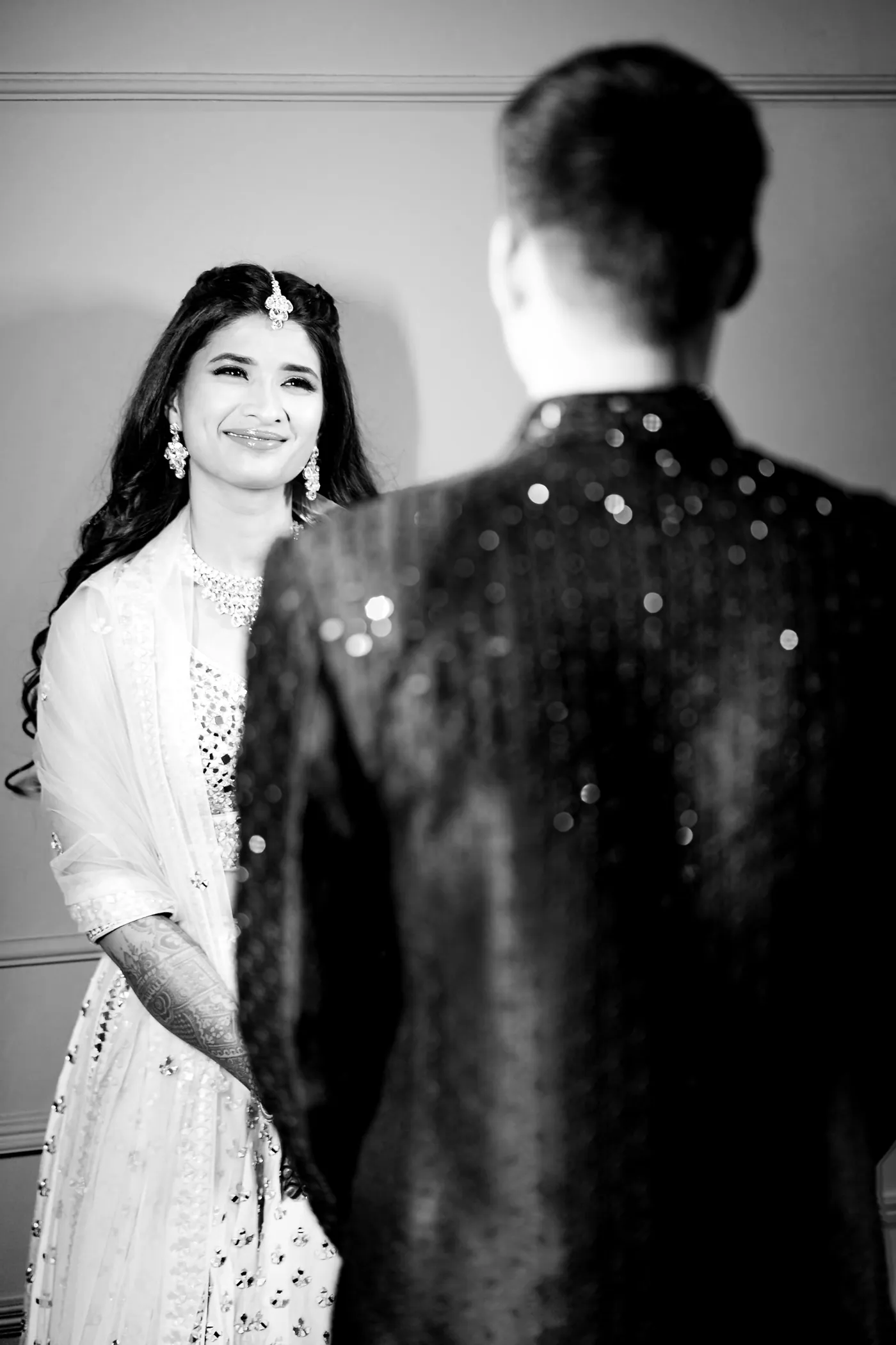In black and white, Medha smiles broadly at Stefan, who stands with his back to the camera