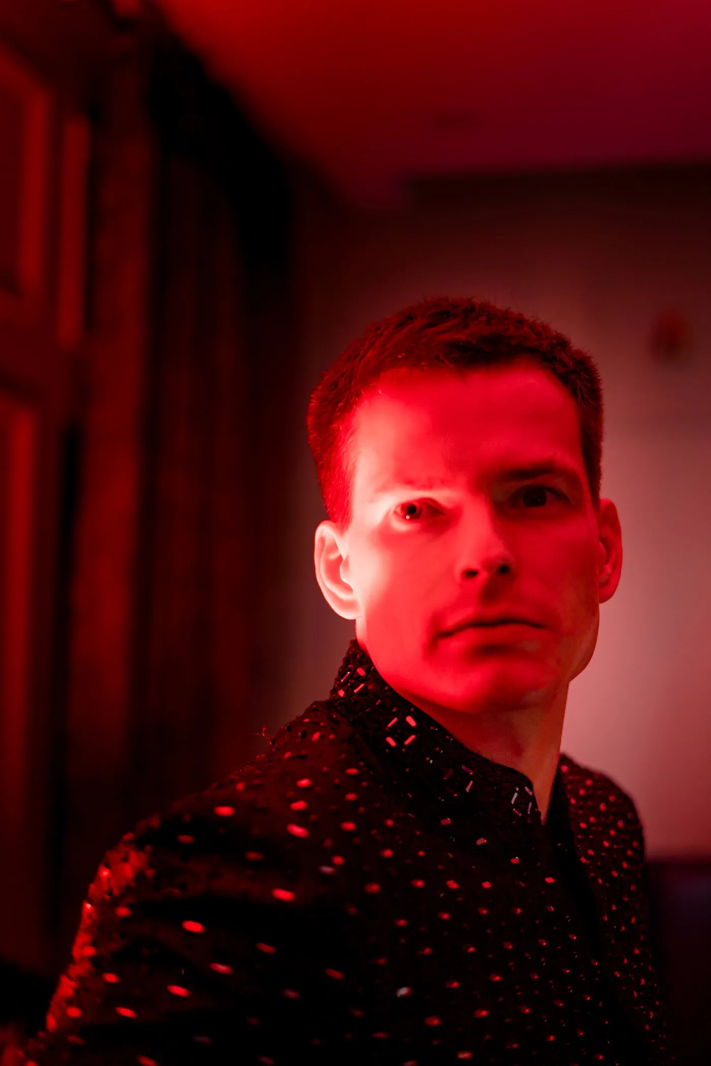 Stefan's face is lit in deep red against a dark background