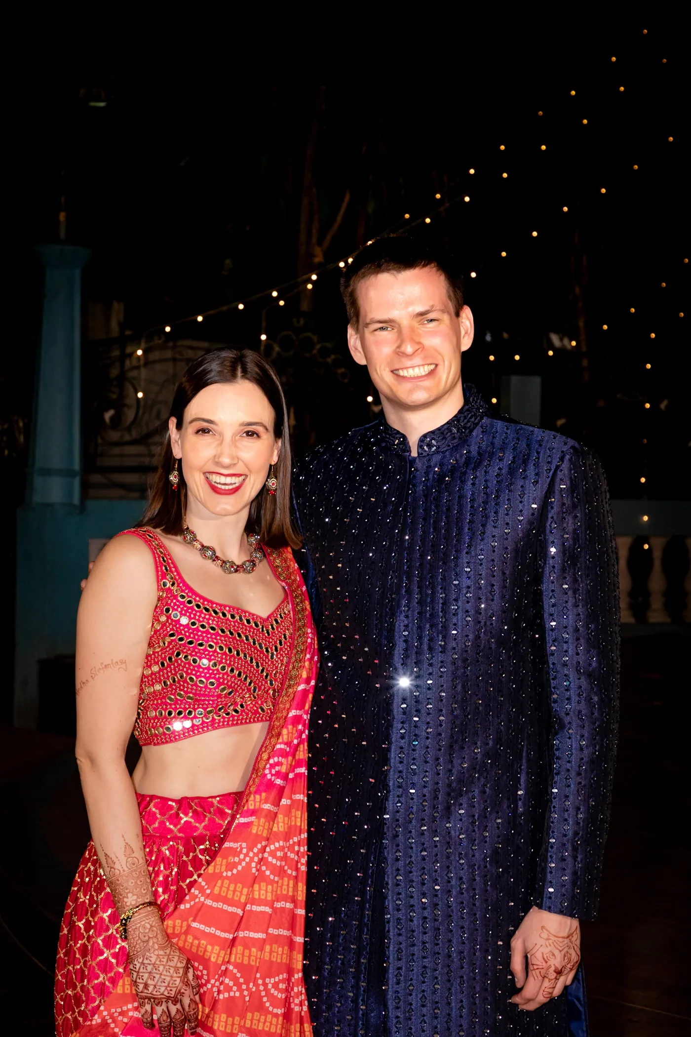 Stefan in his navy sherwani stands with his sister, who wears a pink and orange lehenga