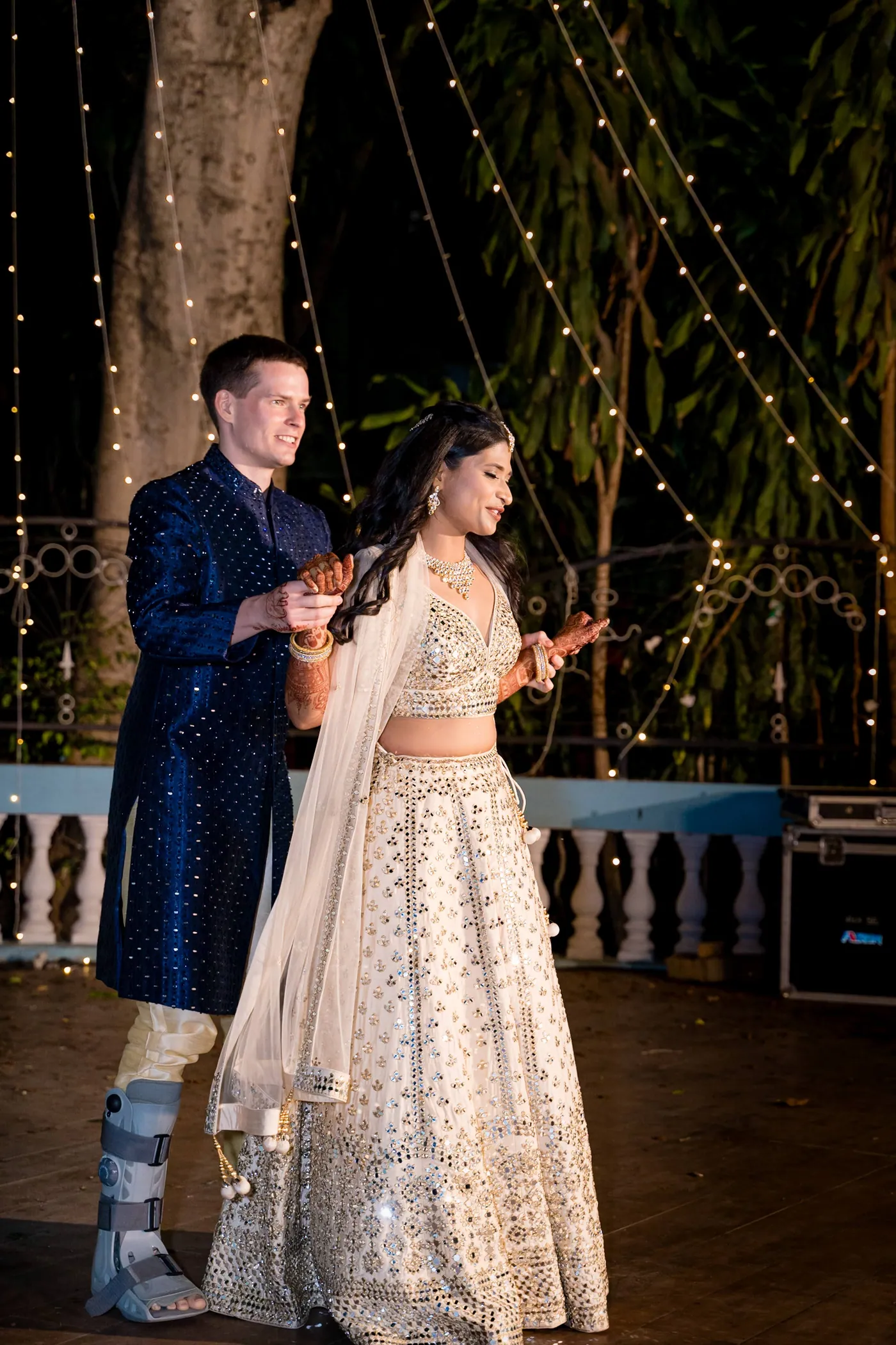 Stefan in navy and Medha in cream dance close together as the medical boot on his ankle shows
