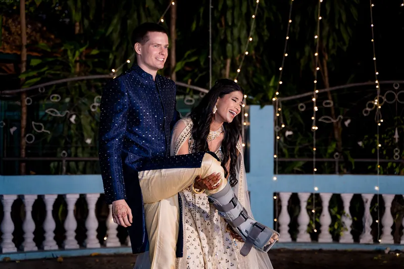 Medha laughs as she holds up Stefan's leg in its medical boot on the dance floor at The Bangalore Club