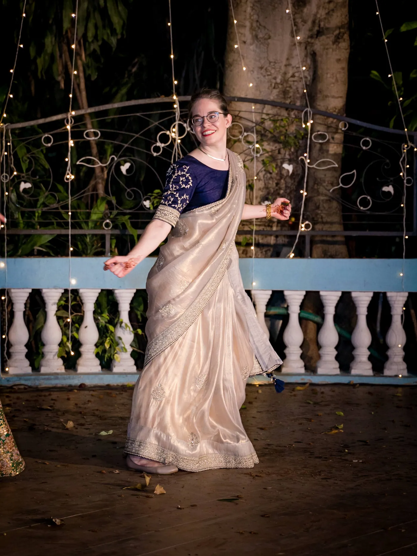 A woman in a cream sari and a blue blouse spins on the dance floor