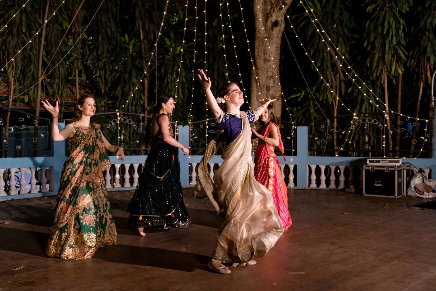 Women in green and gold dress saris dance across the floor