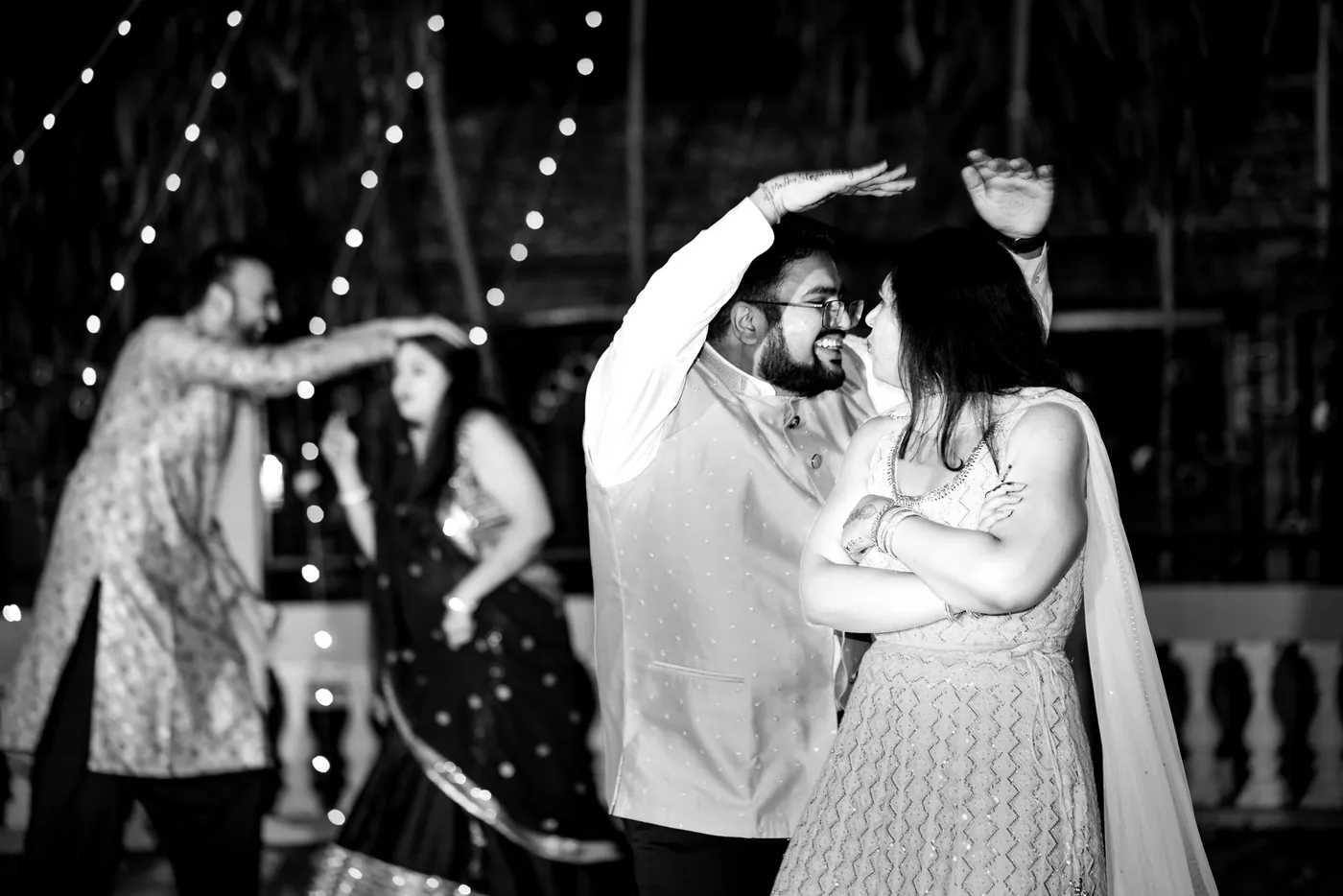 In black and white, a couple of guests dance close with their heads together
