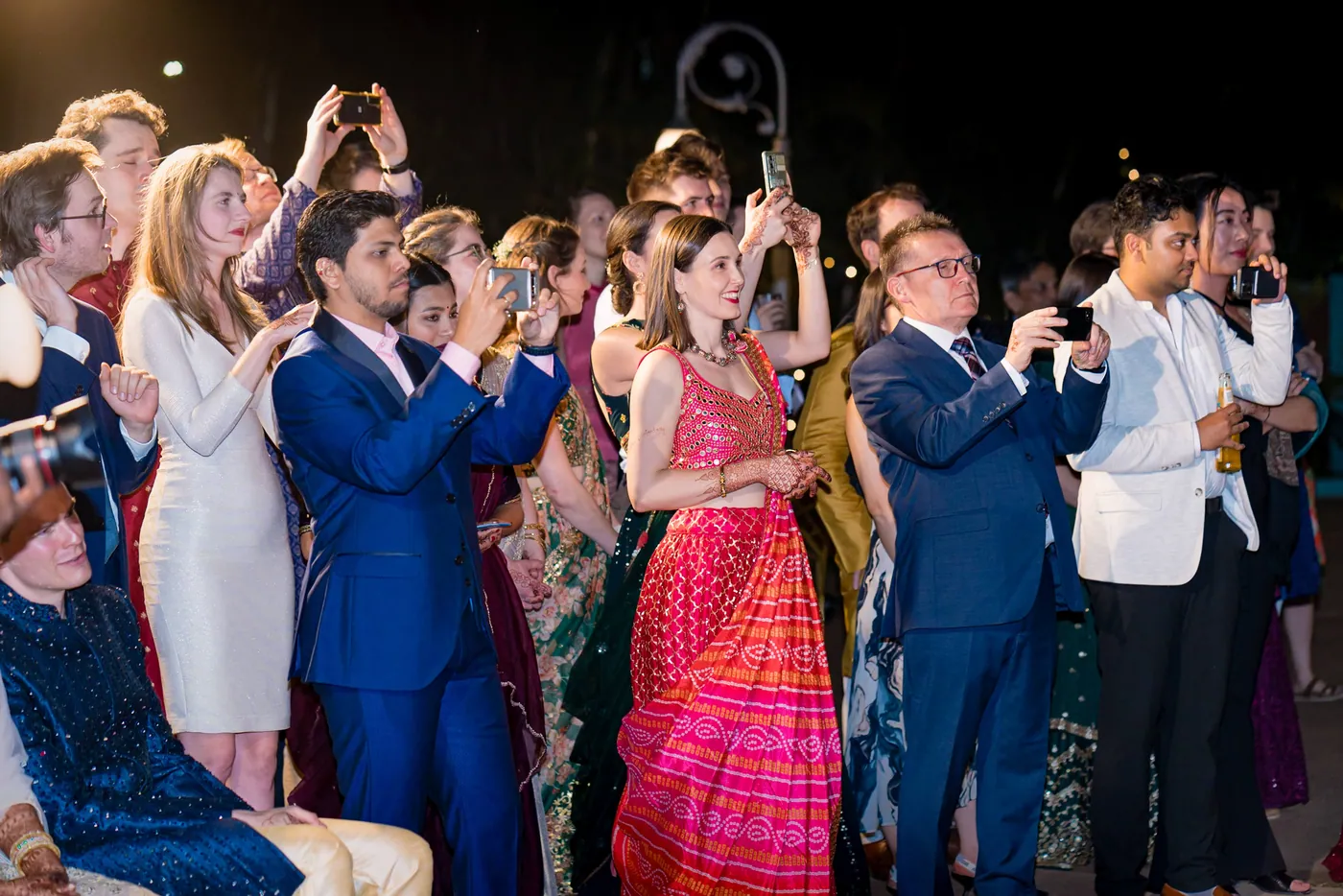 Guests crowd the edge of the dance floor lifting their phones to film