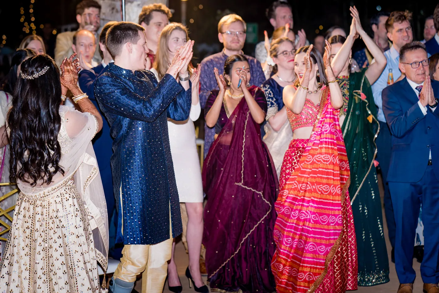 Stefan and Medha dance among a tightly packed crowd in navy and cream