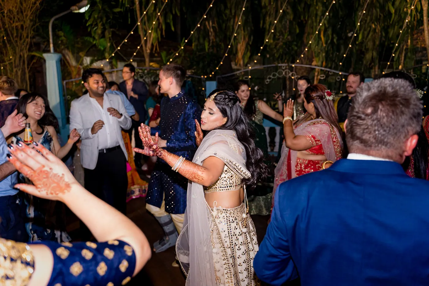Guests dance in a crush, with Medha in the middle in her cream lehenga and Stefan nearby