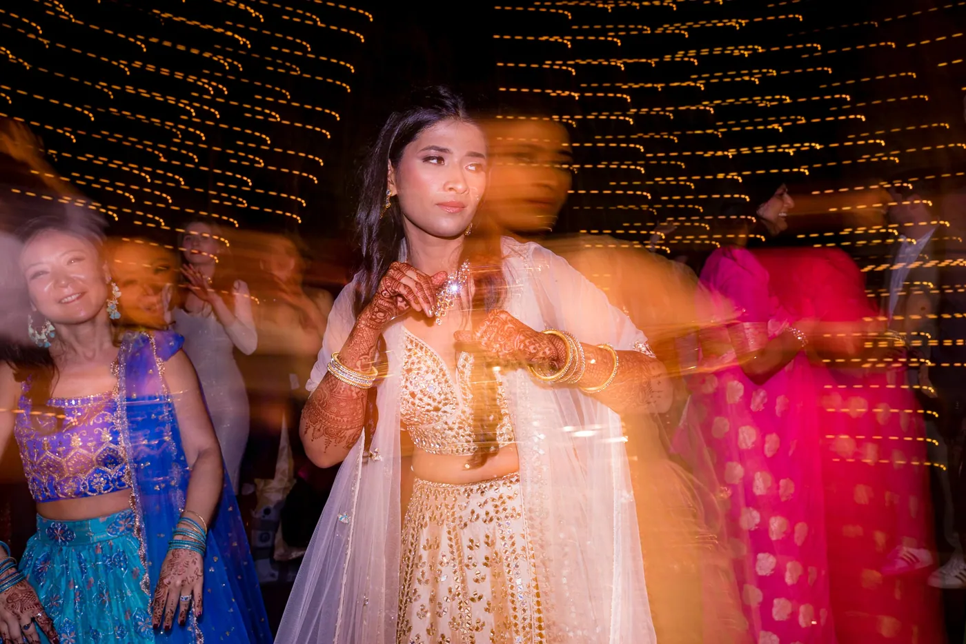 Medha dances in a blur with her hands out, a smear of colour from other dancers all around her