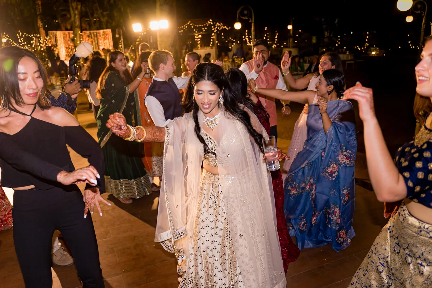 Medha dances in the middle of a crowded floor with women around her in saris and lehengas