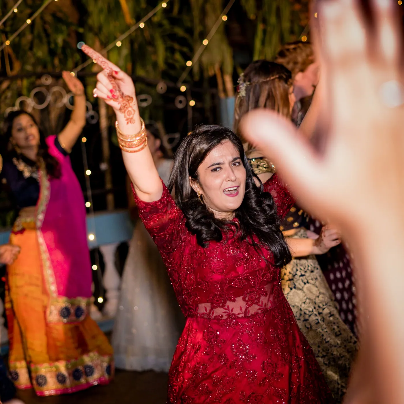 A woman in a red dress points with an upraised hand while others dance around her