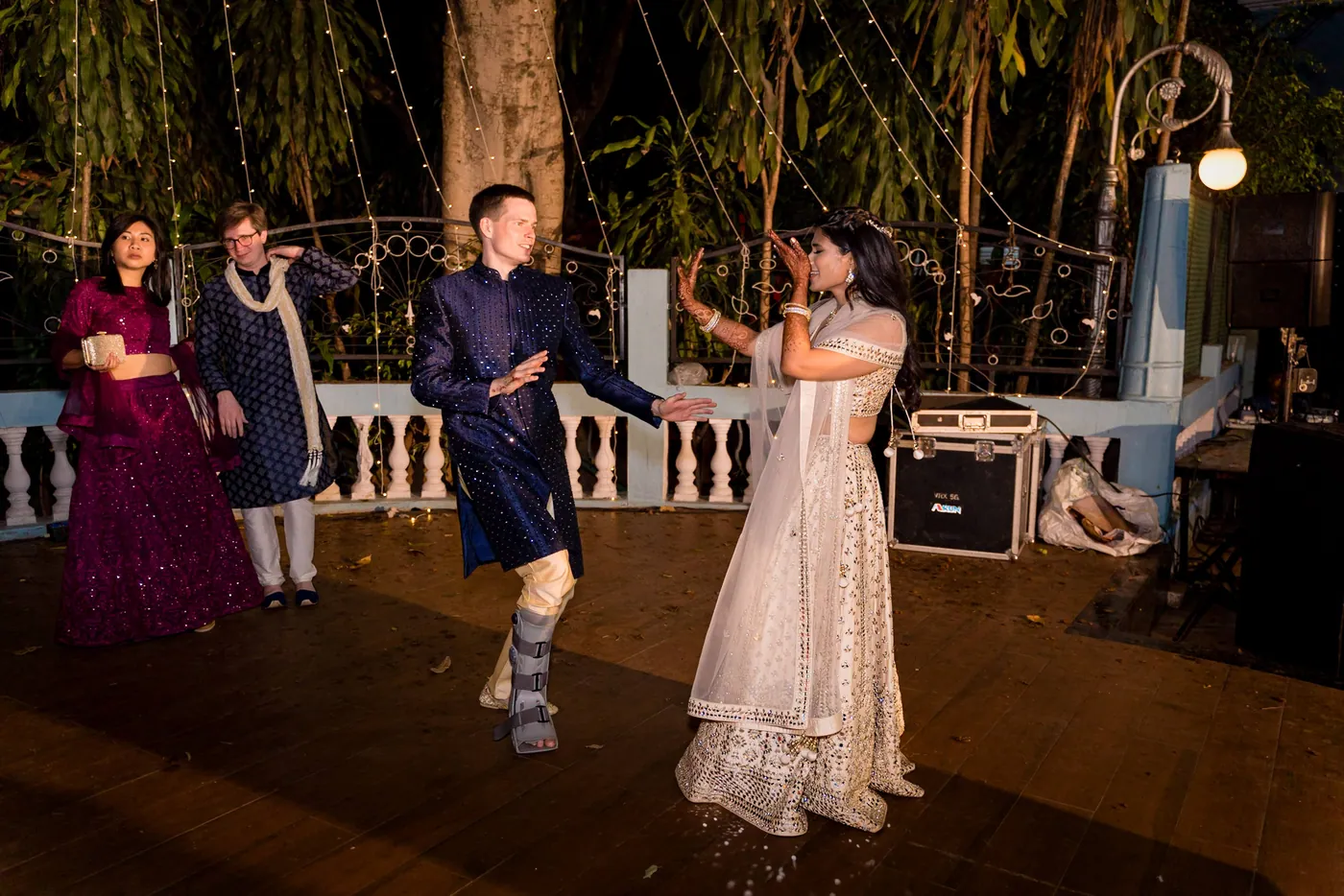 Stefan in navy dances with Medha in cream while a medical boot shows on his lower leg
