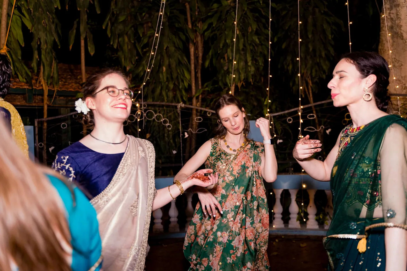 Women in glasses and green and blue outfits dance and smile together