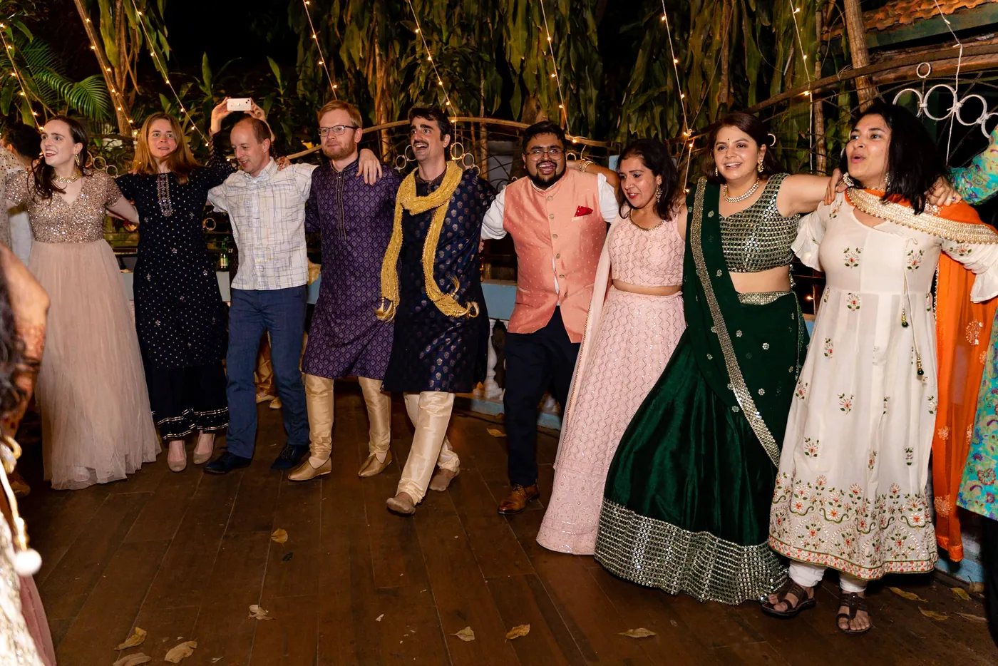 Guests in pastel, green and navy outfits dance in a loose circle
