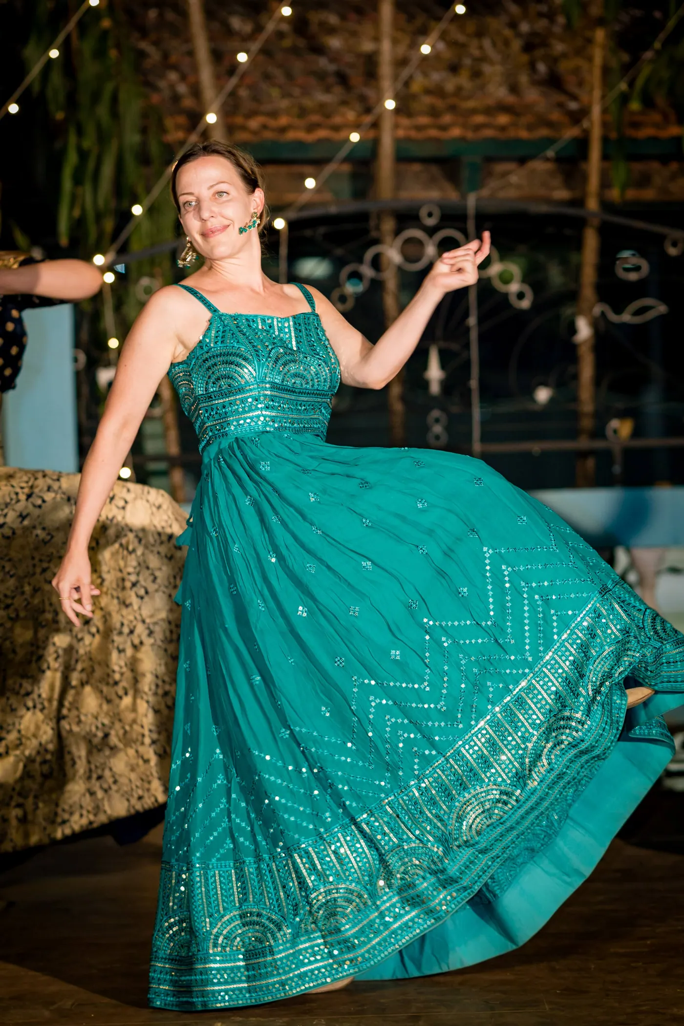 A woman in a teal gown spins and sweeps her arm out across the dance floor
