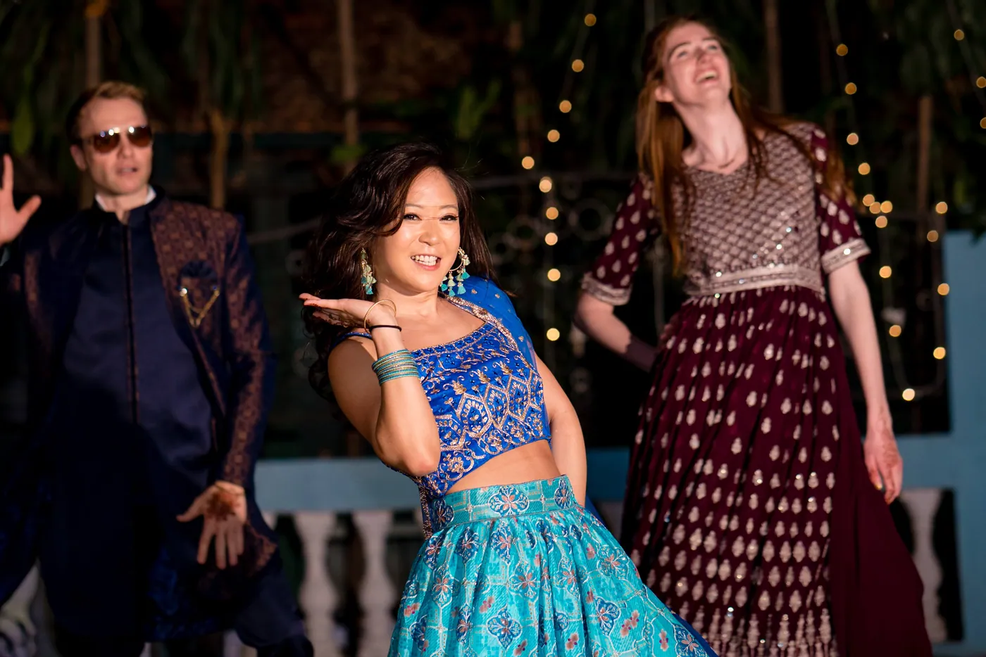 A woman in a blue crop top blows a kiss while two others dance beside a man in sunglasses