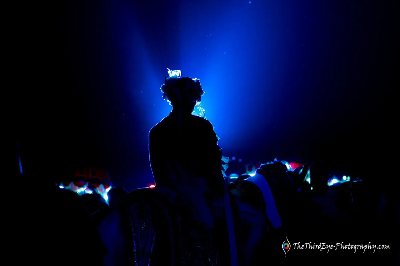 The groom in a turban in silhouette against blue stage haze, a blue LED glow at his feet