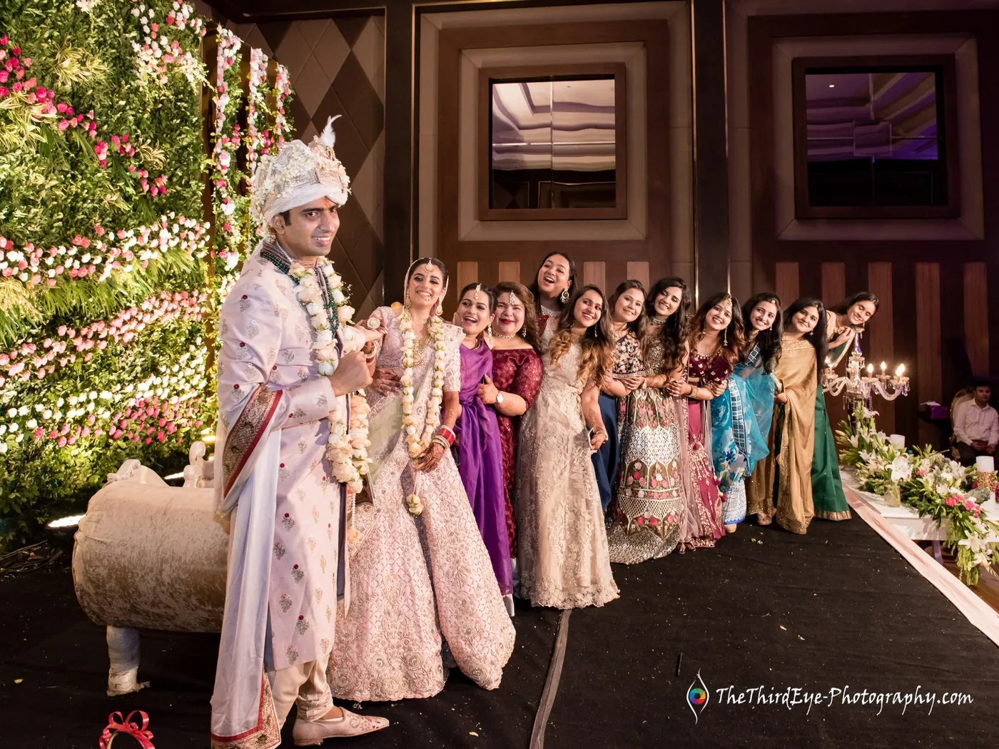 The couple stand at the centre of a long line of relatives on the green floral stage