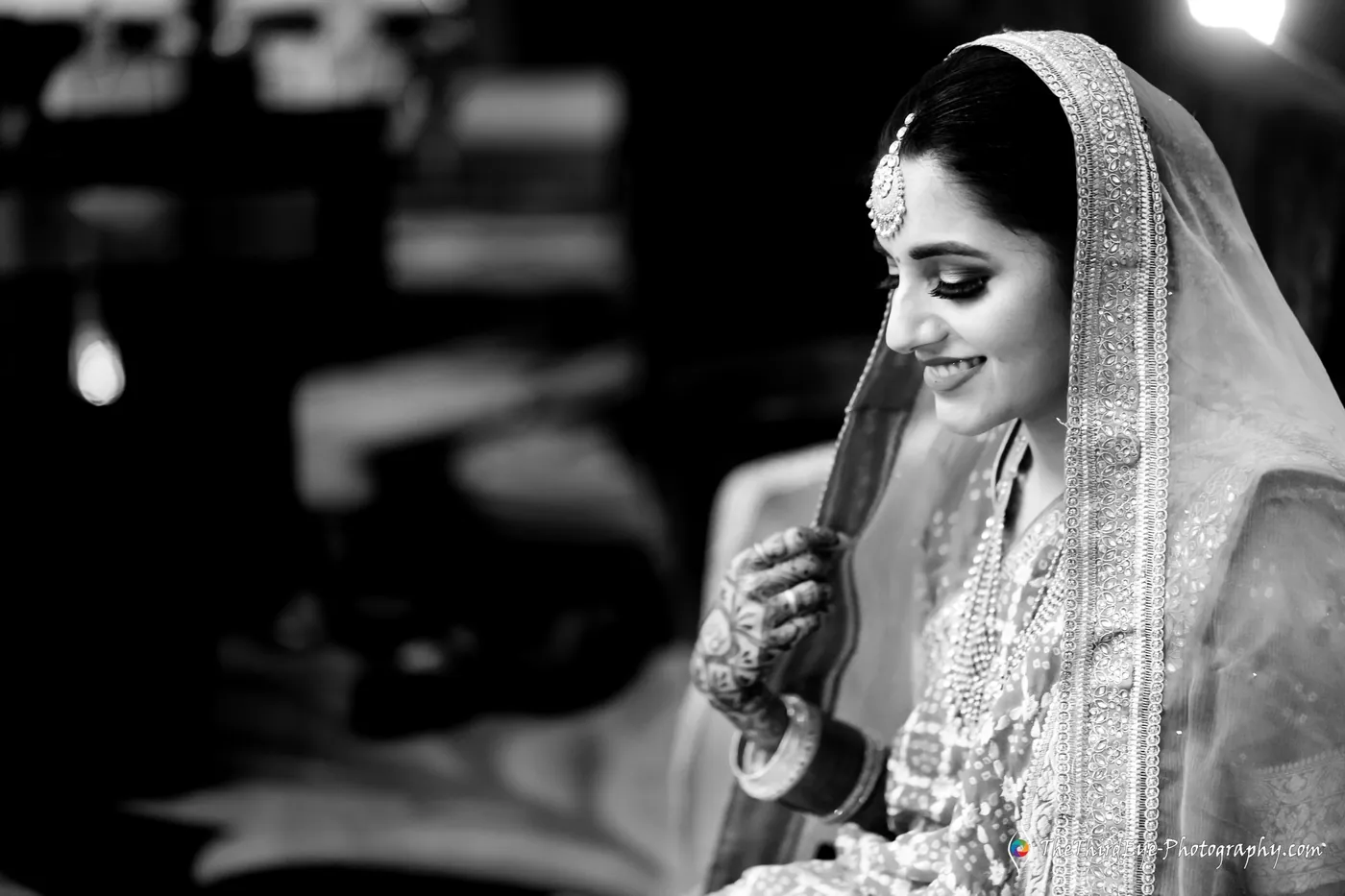 Black and white frame of the bride looking down with a soft smile, her veil over her hair