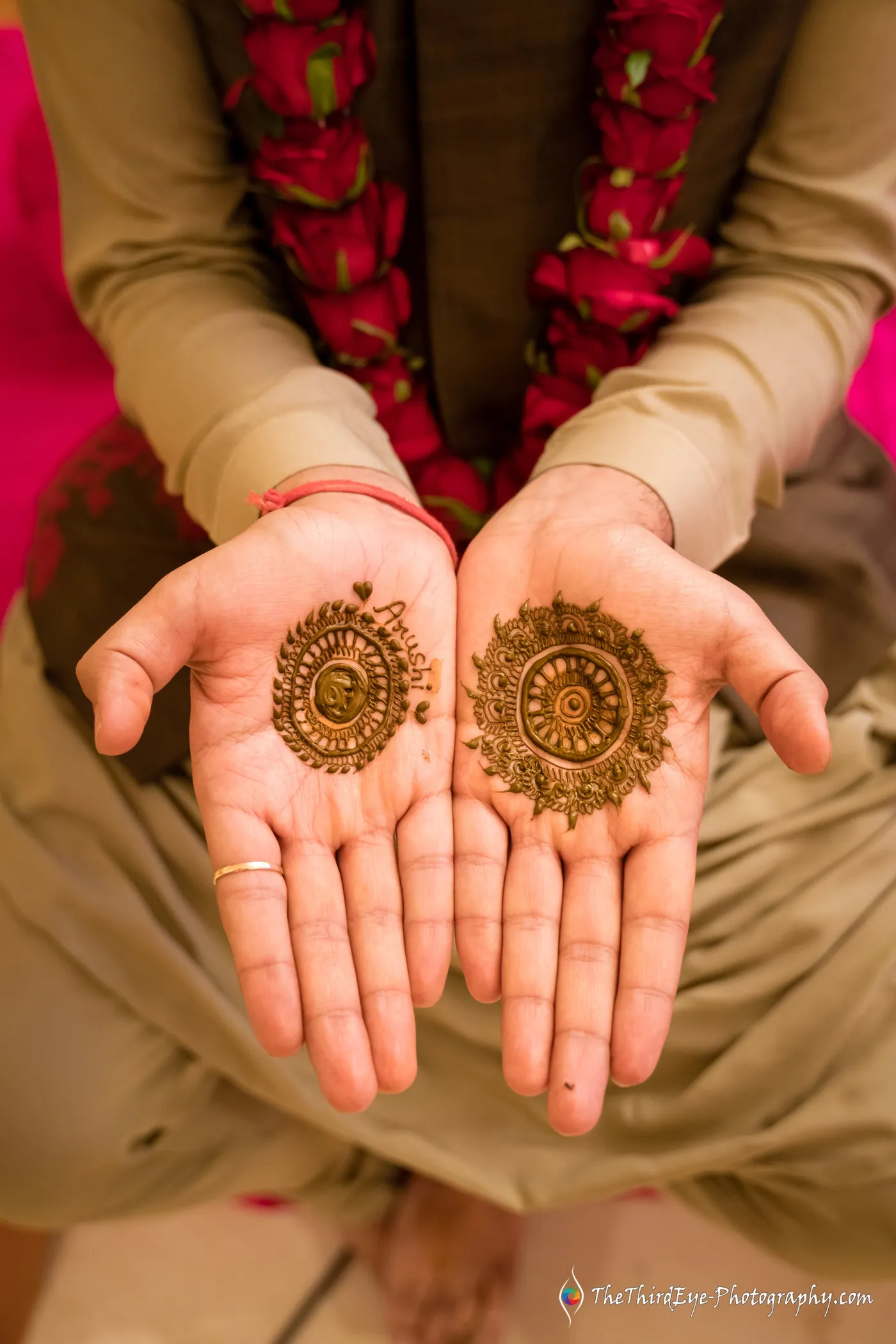 Two open palms painted with round mehendi circles, flower garlands resting below