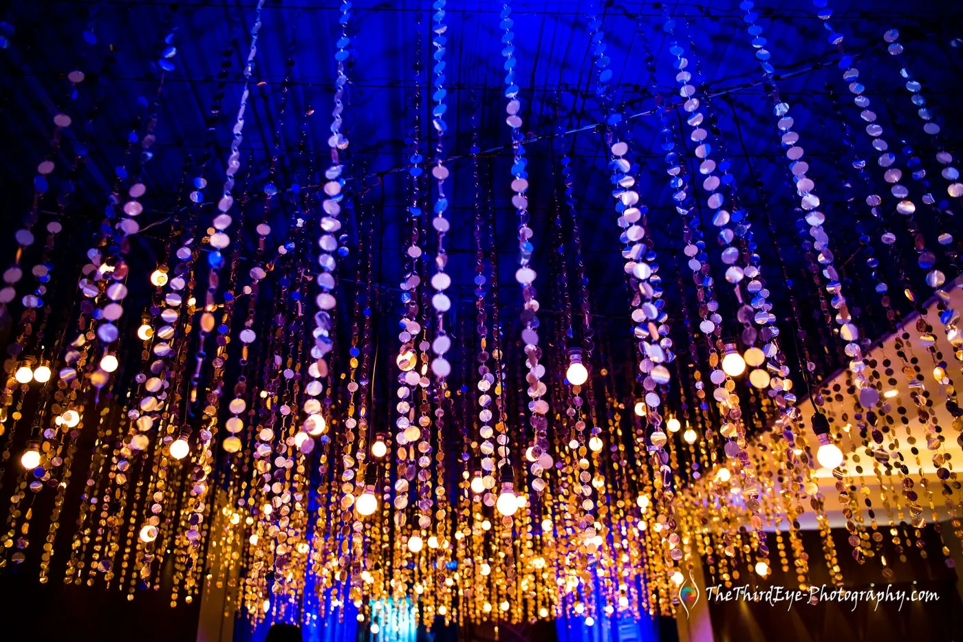Strings of crystal beads hang from the ceiling, glowing gold against deep blue light