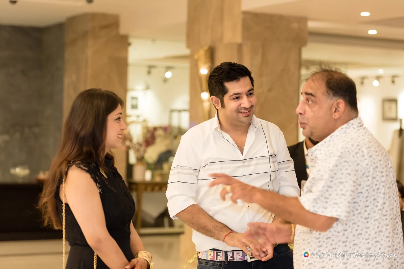 A woman looks on as two men in conversation talk with lively hand gestures