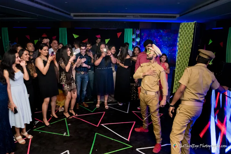 A packed crowd rings the dance floor while two performers in police style uniforms dance among green triangles