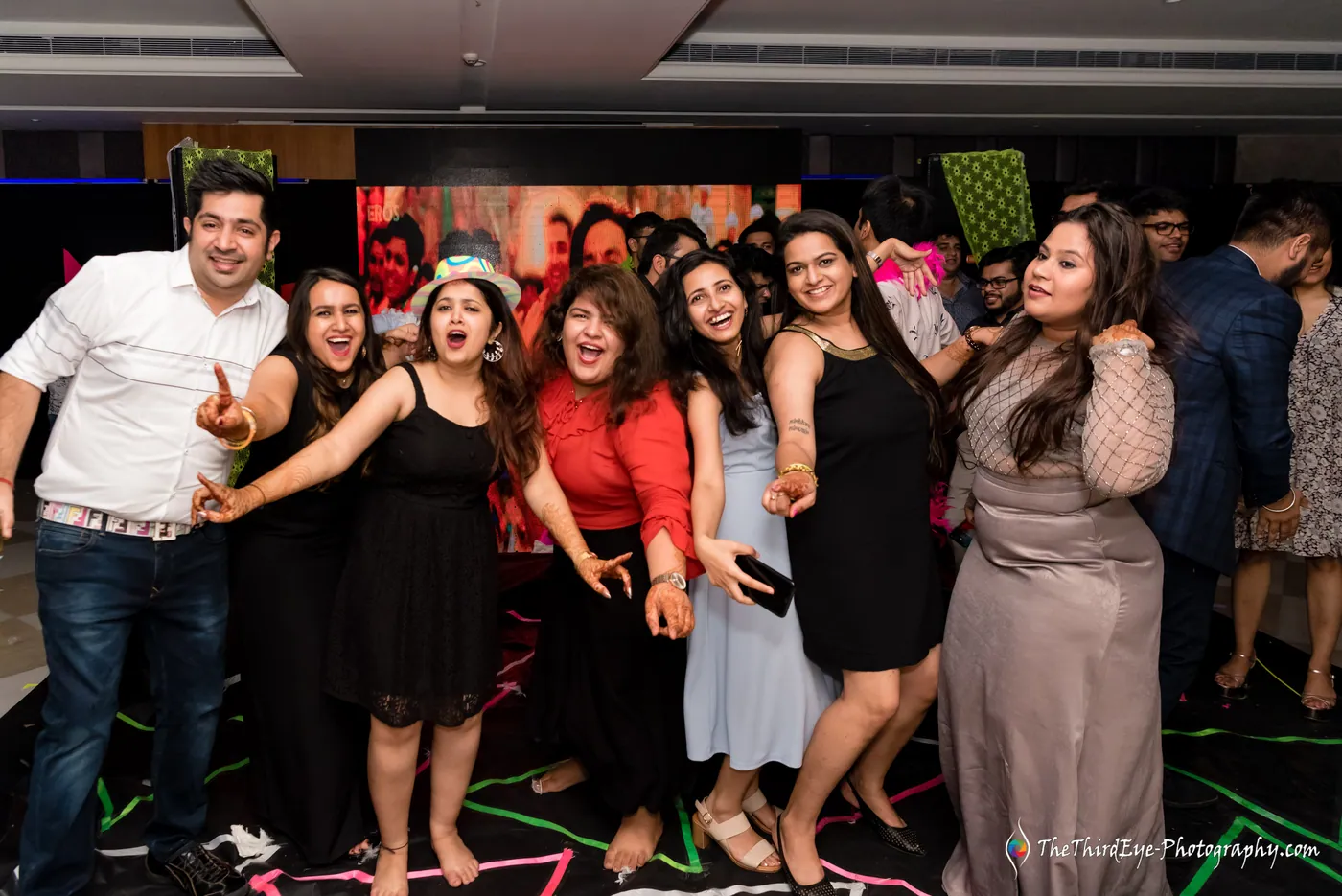 Women on the dance floor stretch out their arms and cheer toward the camera as a man joins in
