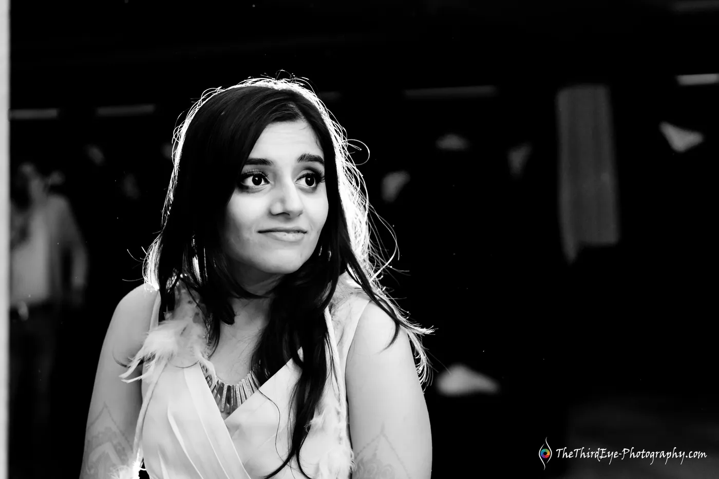 Black and white portrait of a woman with light tracing her hair, glancing to the side in the dark