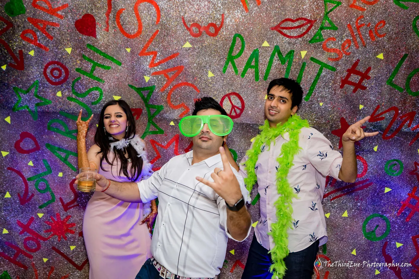 Friends strike dance poses in front of the glowing backdrop that carries the names Ramit and Arushi