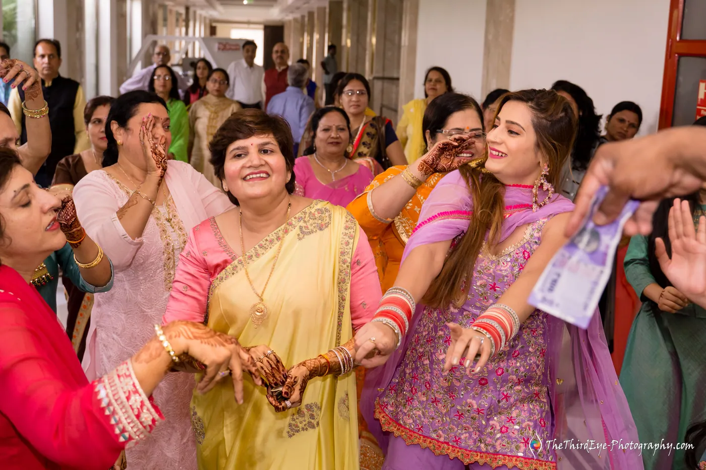Women laugh and show off their hands, one holding up currency notes in the crush