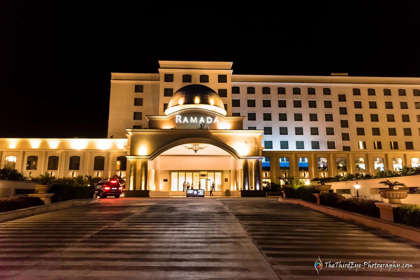 The Ramada hotel entrance glowing against a black night sky, the road empty in front
