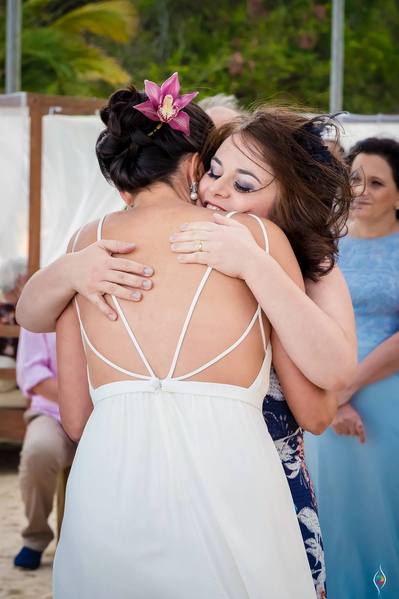 Evy hugs a woman with curly hair, a smiling woman in blue just behind them