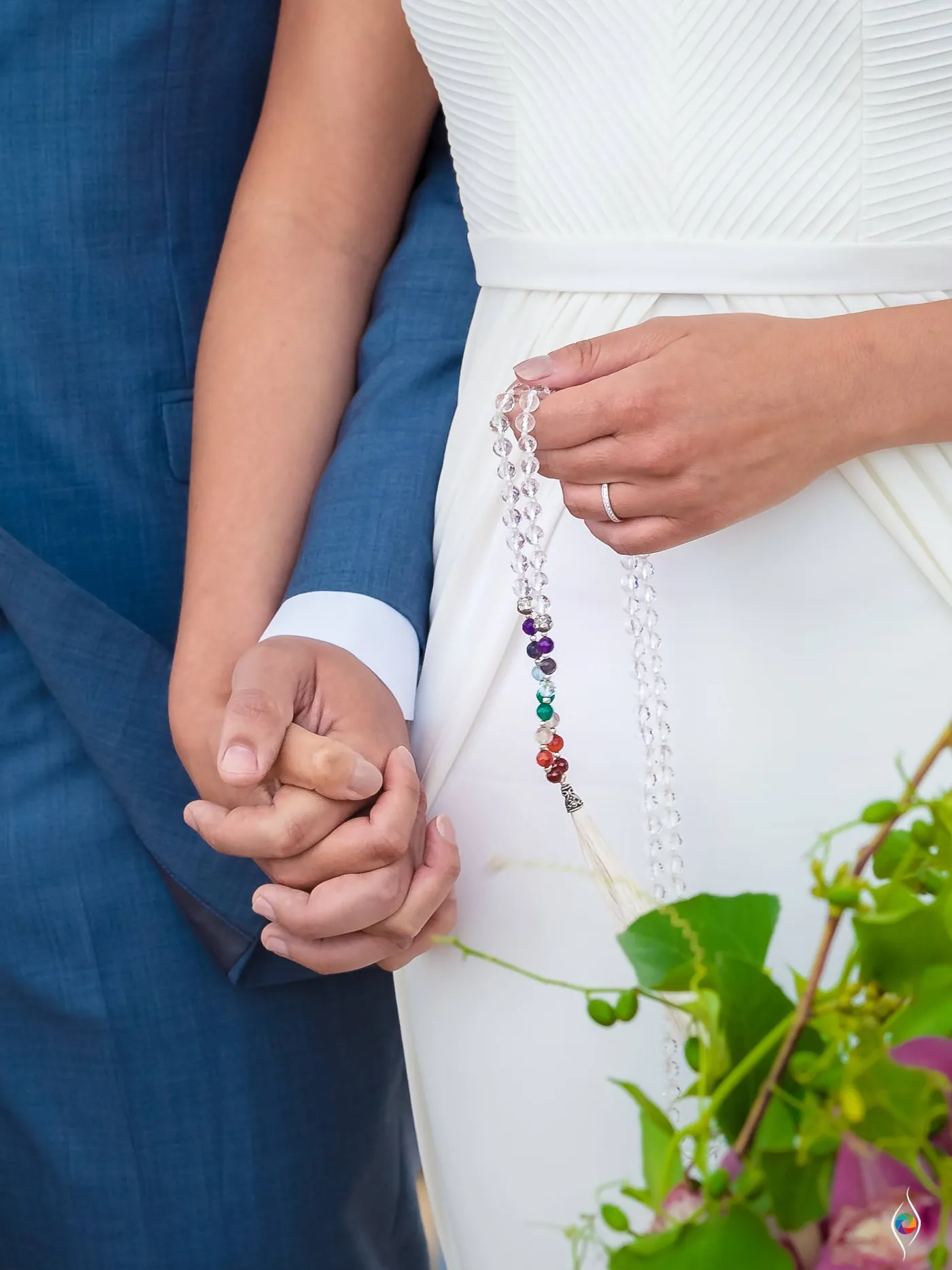 Evy and Thiago hold hands with a string of coloured beads wound around their fingers