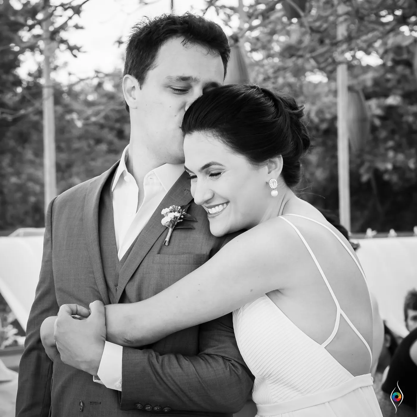 In black and white, Thiago kisses Evy's forehead as she hugs him close and smiles