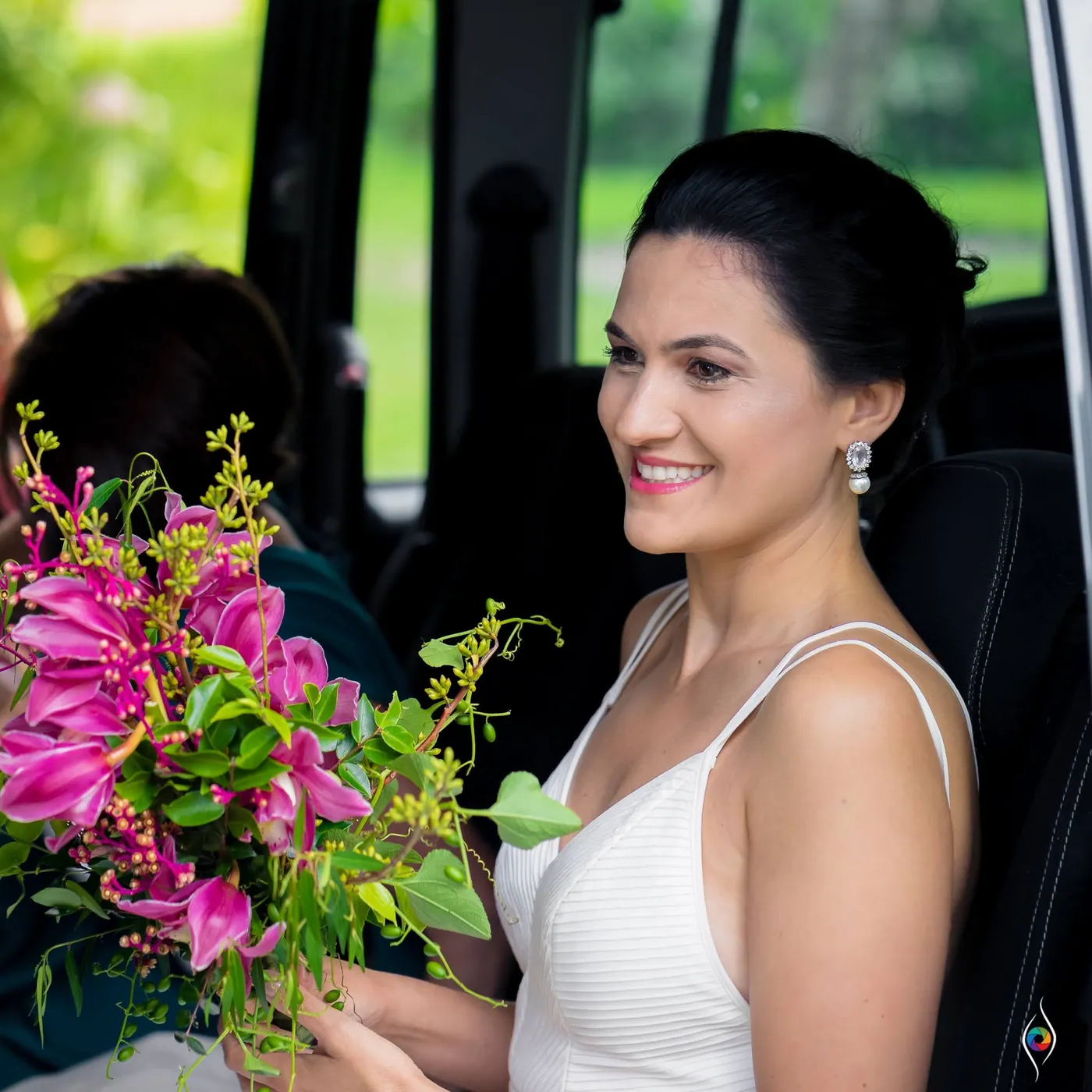 Evy smiles from the doorway of a van, holding a bouquet of pink flowers