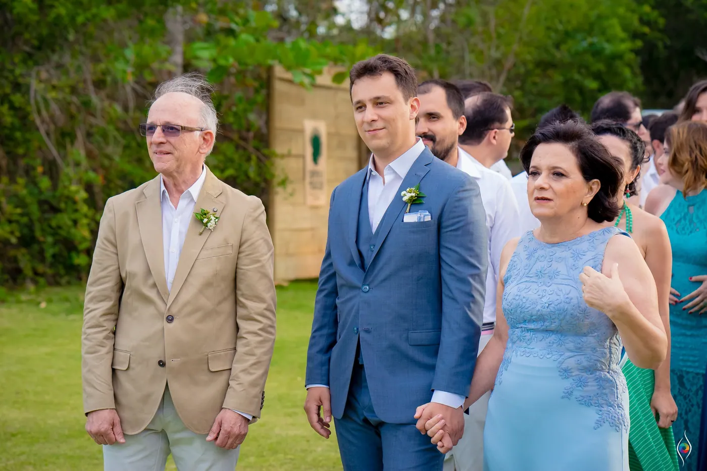 Thiago walks the lawn hand in hand with a woman in pale blue, a man in a beige jacket beside