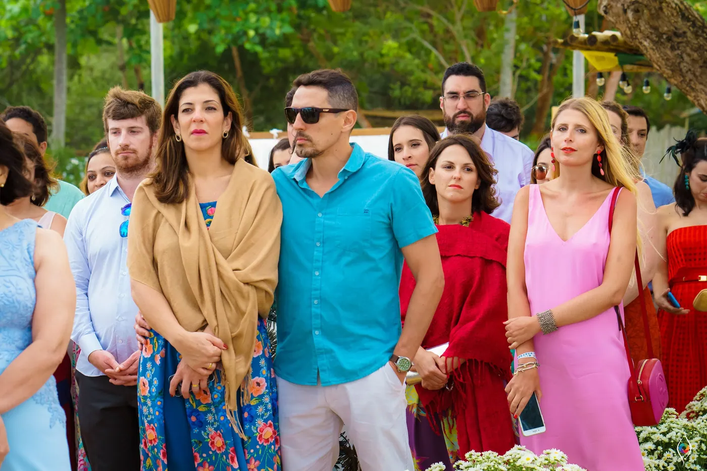 Guests in teal, pink and red watch the ceremony with a mix of smiles and concentration
