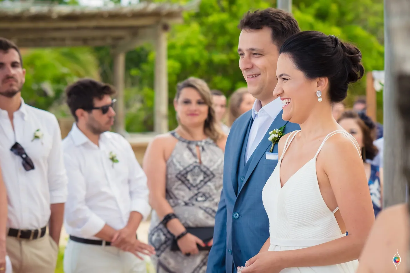 Thiago and Evy smile as guests in white shirts stand close around them