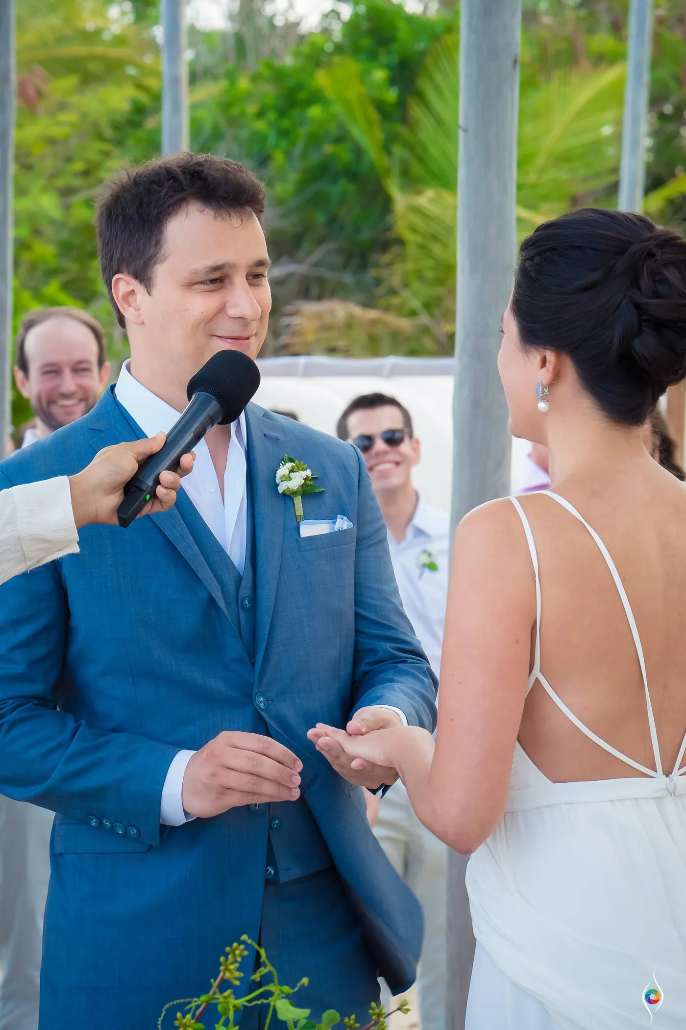 Thiago in a blue suit holds out his palm as a microphone enters the frame
