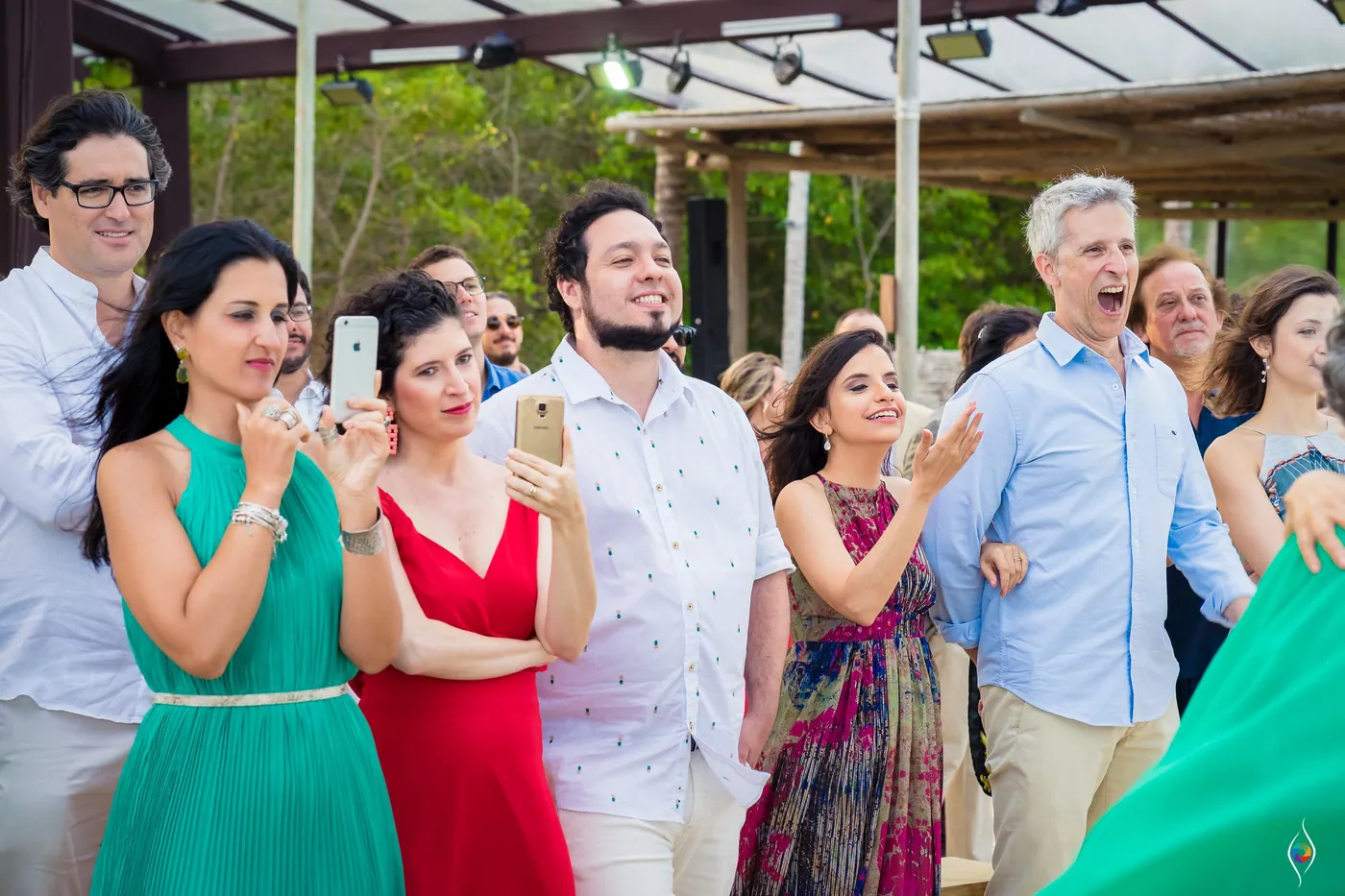 Guests lift phones to film while others laugh and applaud at the ceremony
