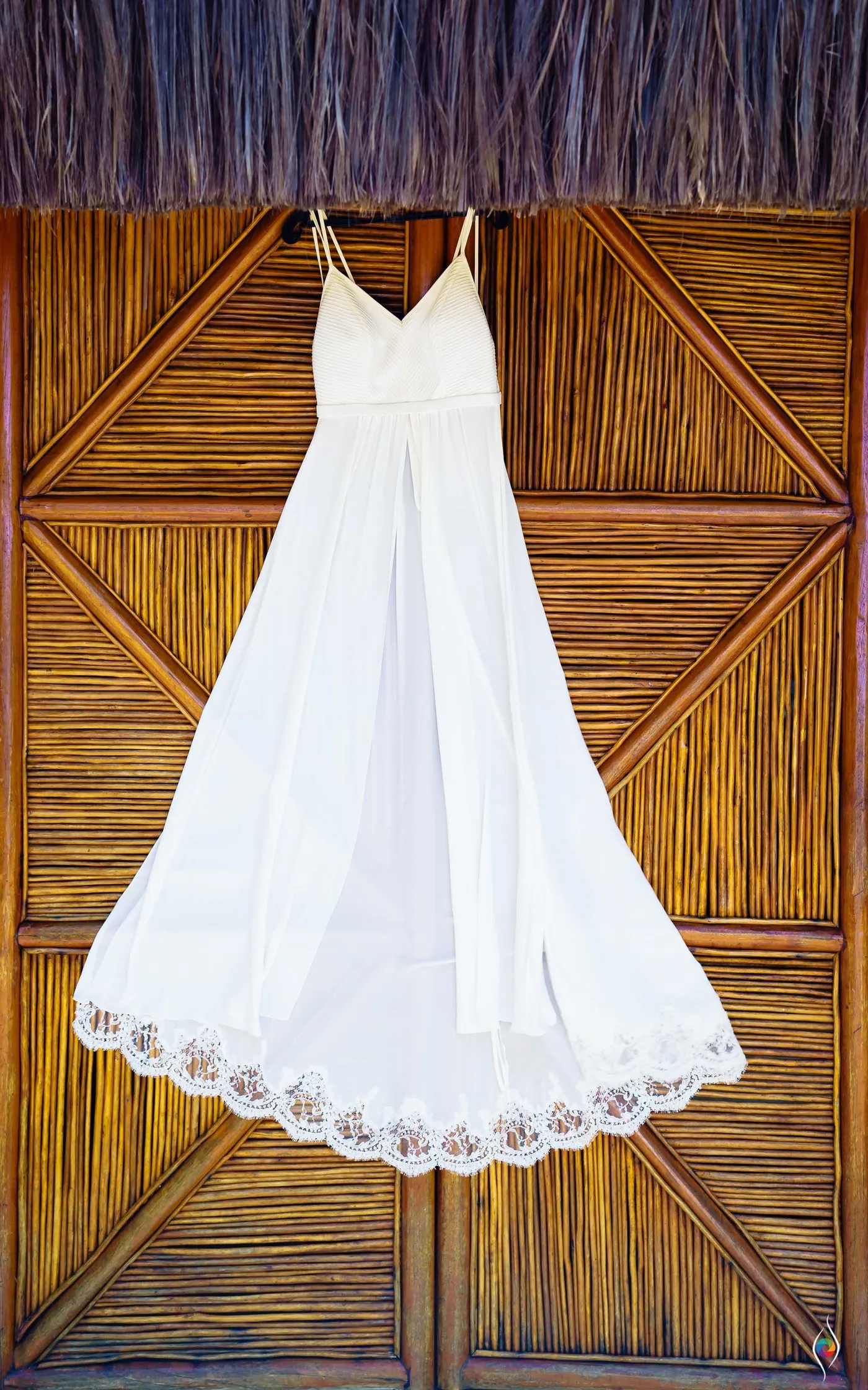 The wedding dress hangs on a wooden door, its lace hem spread open