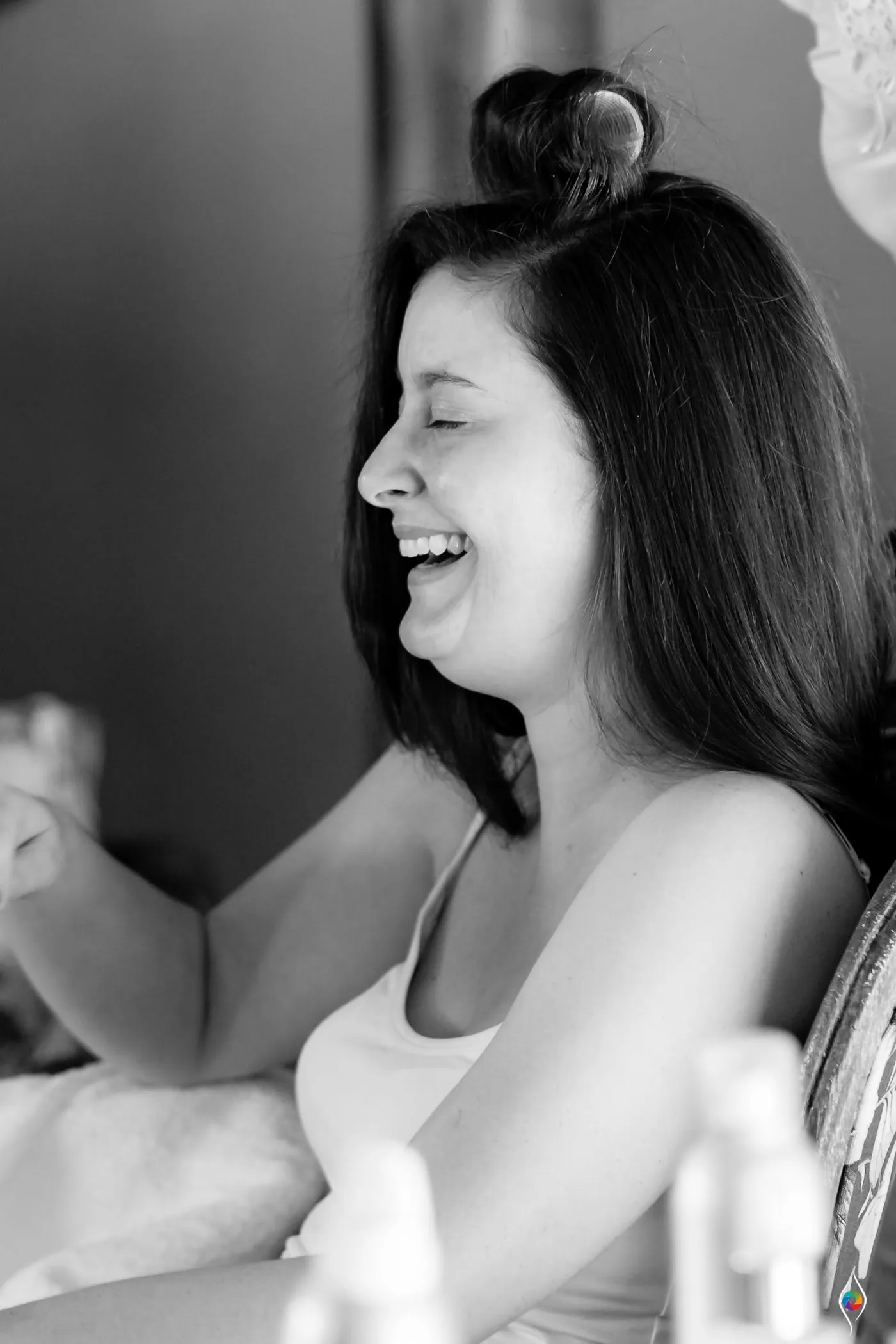 Black and white close view of a woman mid laugh, her hair in a top knot