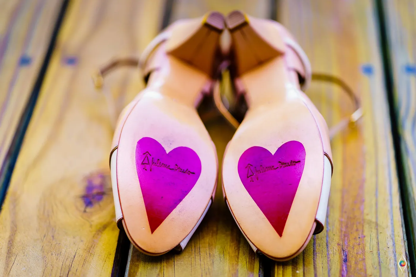 Bridal shoes turned over to show hot pink hearts painted on the soles
