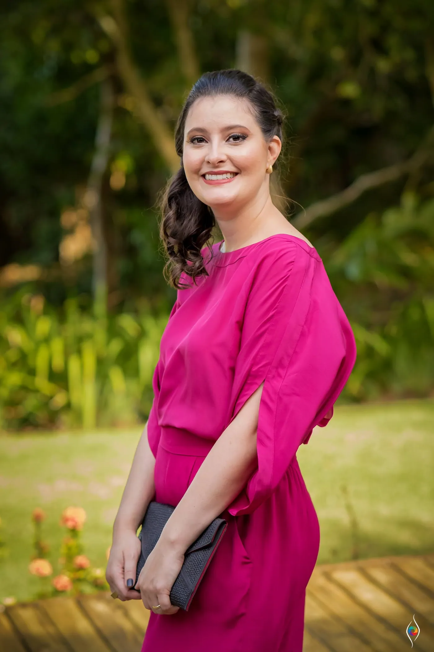 A woman in a bright pink top smiles on a deck in soft afternoon light
