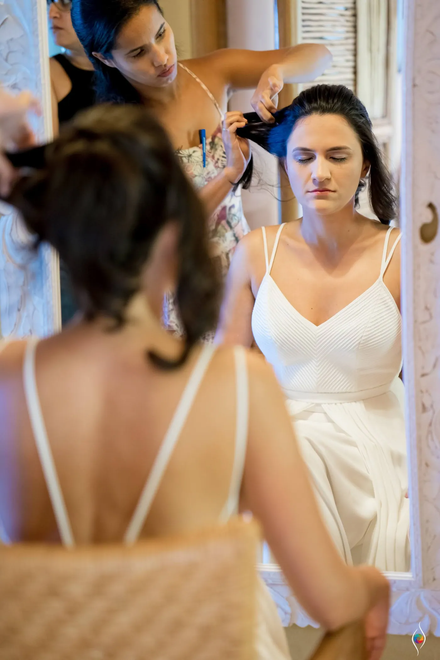 Helpers tend to Evy's hair as she stands in her white dress with her eyes closed